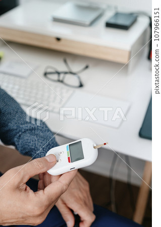 man in the office measures his blood glucose level 107966151