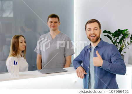 Grateful patient. Man standing at the reception of dental clinic and very pleased for the treatment. Grateful patient. Man standing at the reception of dental clinic and very pleased for the treatment. 107966401