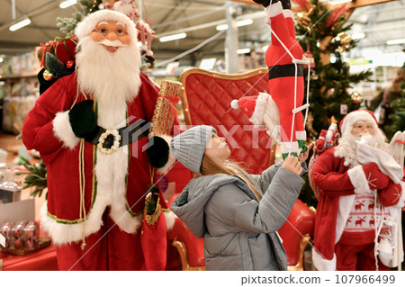 A child is surrounded by Santa Clauses in a store A child is surrounded by Santa Clauses in a store 107966499