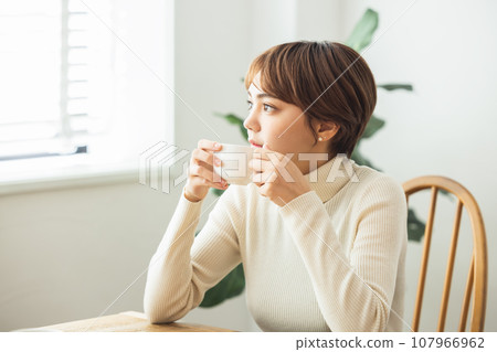 A woman who drinks coffee in a room A woman who drinks coffee in a room 107966962