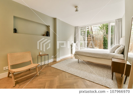 a bedroom with a bed, chair and tv on the wall in it's corner next to a window a bedroom with a bed, chair and tv on the wall in it's corner next to a window 107966970