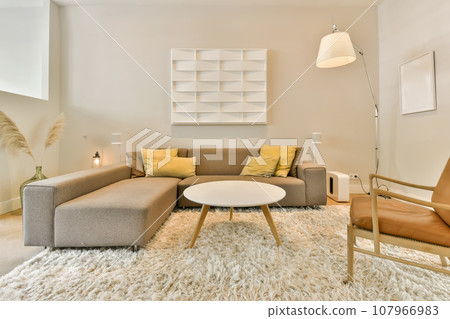 a living room with white furnishs on the floor and two chairs in the corner, one is brown 107966983