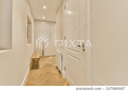 a long hallway with white walls and wood flooring on either side by side, leading to the other rooms a long hallway with white walls and wood flooring on either side by side, leading to the other rooms 107966987
