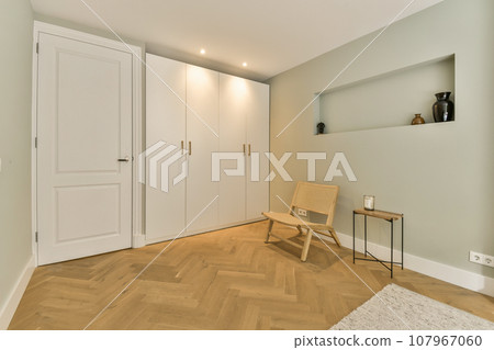 a room with wood flooring and white closets on the right side, there is a wooden chair in front of the door a room with wood flooring and white closets on the right side, there is a wooden chair in front of the door 107967060