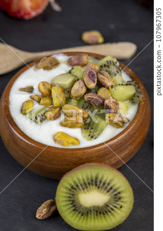fresh green yogurt with pieces of kiwi and pistachios 107967305