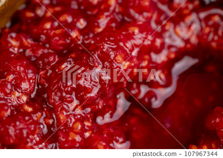crumpled juicy red raspberries in a wooden bowl 107967344