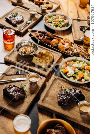 Tasty dishes in restaurant with beef steak, salad and barbecue chicken wings. Food menu concept 107967634