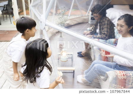 Glamping image: Parent and child communicating through the window of a dome tent 107967844