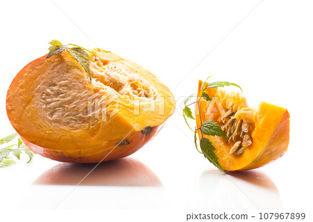 A piece of ripe orange pumpkin with seeds on a white background. 107967899