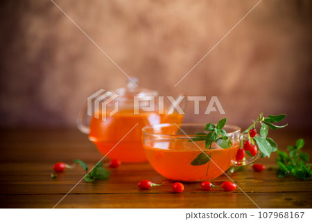 Prepared drink from ripe goji berries in a glass cup and teapot 107968167