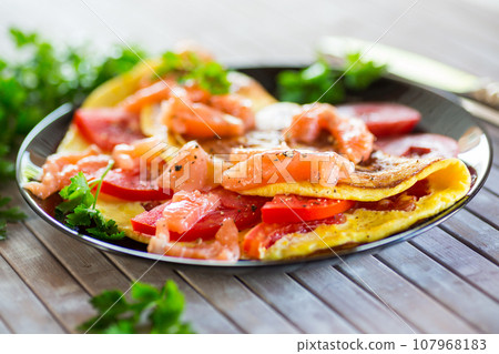 Fried omelette with tomatoes, vegetables and pieces of lightly salted red fish. Fried omelette with tomatoes, vegetables and pieces of lightly salted red fish. 107968183
