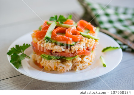 Boiled white rice with salted red fish, cucumbers and other vegetables with herbs in a plate. 107968184
