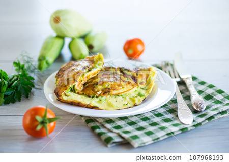 Fried omelet with zucchini, on a wooden table. 107968193