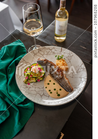 Sea bass or dorado fillet with baked zucchini and sauce on a gray plate Sea bass or dorado fillet with baked zucchini and sauce on a gray plate 107968208