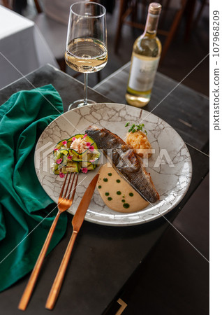 Sea bass or dorado fillet with baked zucchini and sauce on a gray plate Sea bass or dorado fillet with baked zucchini and sauce on a gray plate 107968209