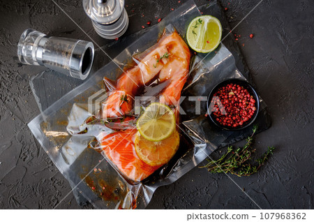 Raw salmon steak with spices and herbs ingredients on black background 107968362