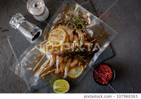 Raw shrimp with spices and herbs ingredients on black background Raw shrimp with spices and herbs ingredients on black background 107968363