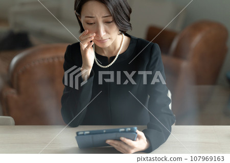 一名婦女透過看平板電腦回憶死者 107969163