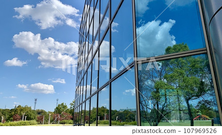 Blue sky and park scenery reflected in the curtain wall (glass wall of a building) <Aichi Health Forest Park Exchange Center/Aichi 107969526