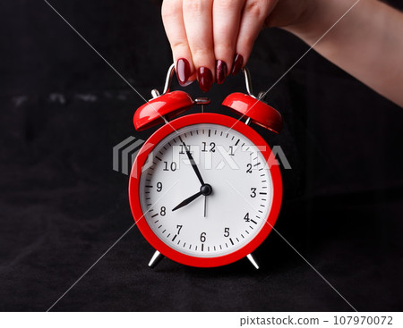 Female arm hold up red alarm clock 107970072