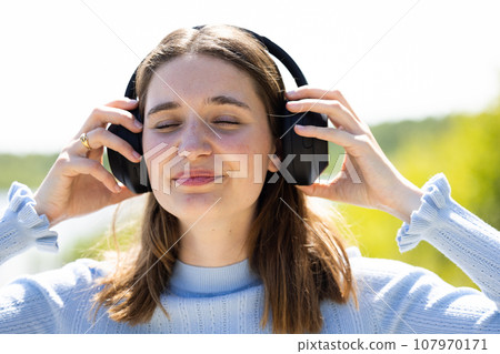 Portrait of a cheerful stylish young millennial woman wearing denim jacket standing outside Portrait of a cheerful stylish young millennial woman wearing denim jacket standing outside 107970171