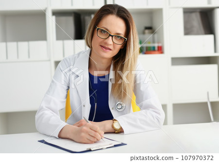 Beautiful smiling female doctor sit at workplace 107970372