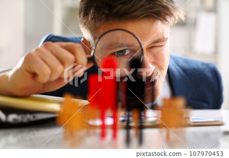 Man in suit look thru loupe on statuettes closeup 107970453