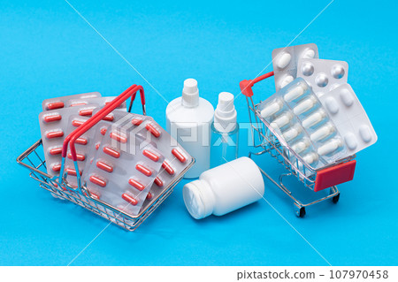 Pills and Capsules in Shopping Cart on Blue Background 107970458