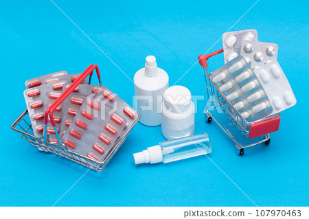 Pills and Capsules in Shopping Cart on Blue Background 107970463