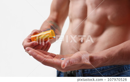 Fitness man pours pills from the jar into Fitness man pours pills from the jar into 107970526