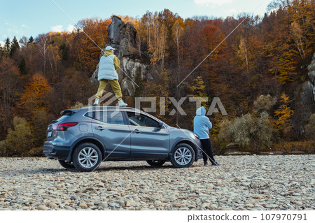 woman on the car man near stopped at mountain river beach autumn season 107970791