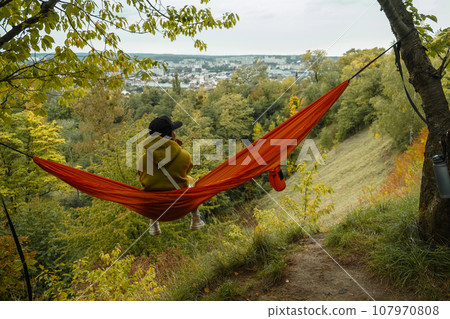 woman view from behind sitting on the hammock enjoying view 107970808