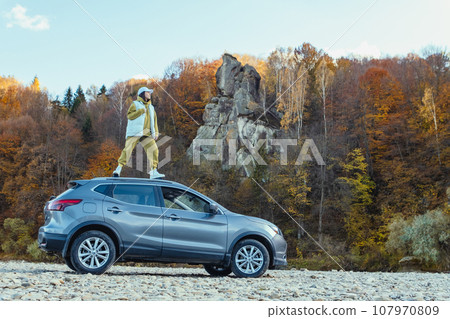 happy woman at car roof enjoying the view of autumn river in carpathian mountains happy woman at car roof enjoying the view of autumn river in carpathian mountains 107970809