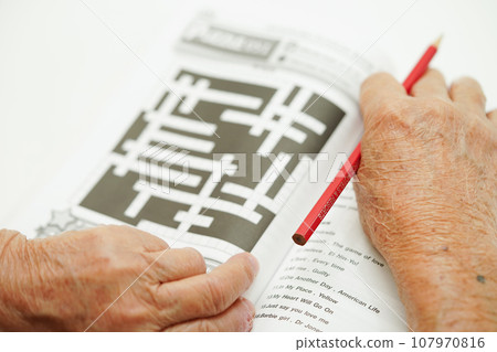 Asian elderly woman playing sudoku puzzle game for treatment dementia prevention and Alzheimer disease. 107970816