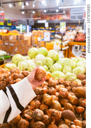 hand taking onion from grocery store shelf 107970885