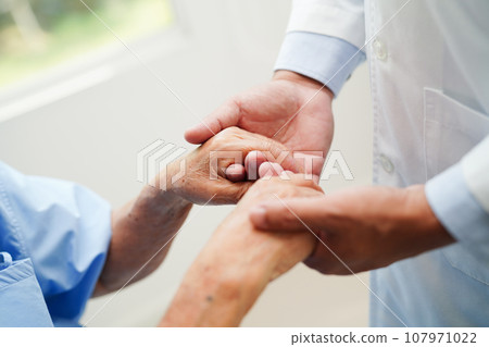 Doctor holding hands Asian elderly woman patient, help and care in hospital. 107971022