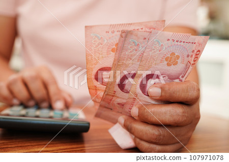 Asian woman counting Thai baht banknote money and holding in hand, investment economy, accounting business and banking. Asian woman counting Thai baht banknote money and holding in hand, investment economy, accounting business and banking. 107971078