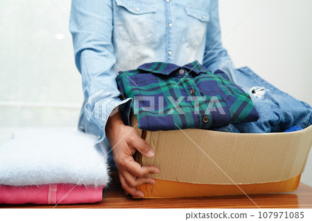 Clothes donations in cardboard box for volunteer. Clothes donations in cardboard box for volunteer. 107971085