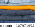 Jeans in different shades of blue and a bright yellow sweater in between. 107971958
