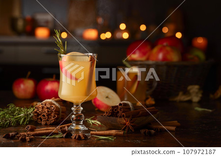 Mulled cider with apples, cinnamon, rosemary, and anise on a background of burning candles. 107972187