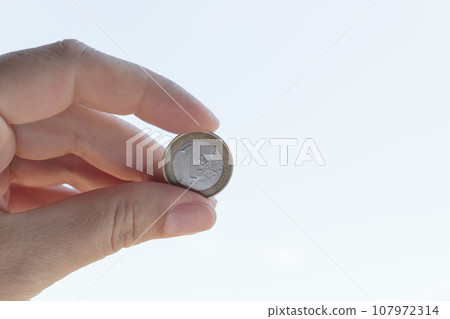 1 euro coin in hand closeup. Cash coin in hand on a white background. 107972314
