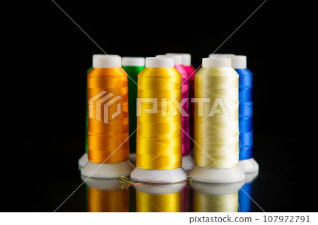 set of different color sewing threads,on black background. 107972791