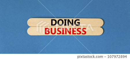 Doing business symbol. Concept words Doing business on wooden stick. Beautiful blue table blue background. Business, motivational Doing business concept. Copy space. 107972894