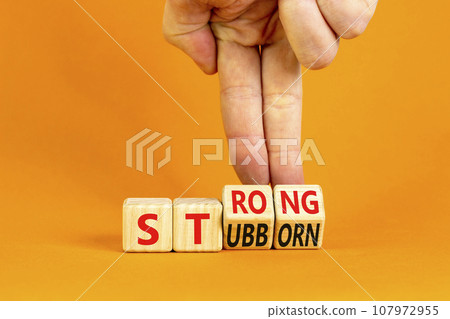 Strong and stubborn symbol. Concept words Strong Stubborn on wooden block. Beautiful orange table orange background. Businessman hand. Business strong and stubborn concept. Copy space. 107972955