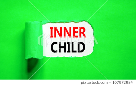 Inner child symbol. Concept words Inner child on beautiful white paper. Beautiful green table green background. Psychological, motivational inner child concept. Copy space. 107972984