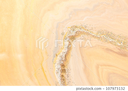 Abstract beige art with gold pink background with brown, beautiful smudges and stains and golden pigment. Beige fluid art texture resembles watercolor or aquarelle. 107973132