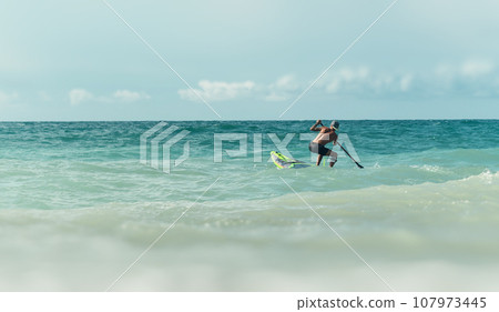 athletic wiry surfer guy swims with a paddle on a sup board in the sea athletic wiry surfer guy swims with a paddle on a sup board in the sea 107973445