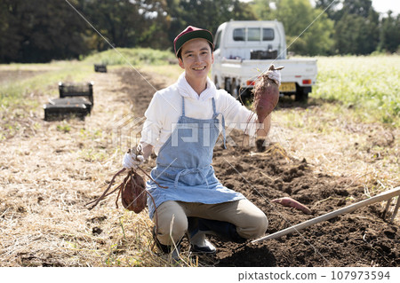 A smiling man holding a sweet potato with both hands 107973594