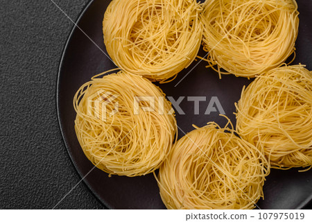 Raw capellini pasta or noodles with salt and spices Raw capellini pasta or noodles with salt and spices 107975019