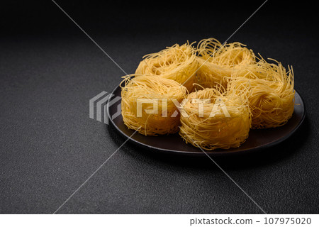Raw capellini pasta or noodles with salt and spices Raw capellini pasta or noodles with salt and spices 107975020